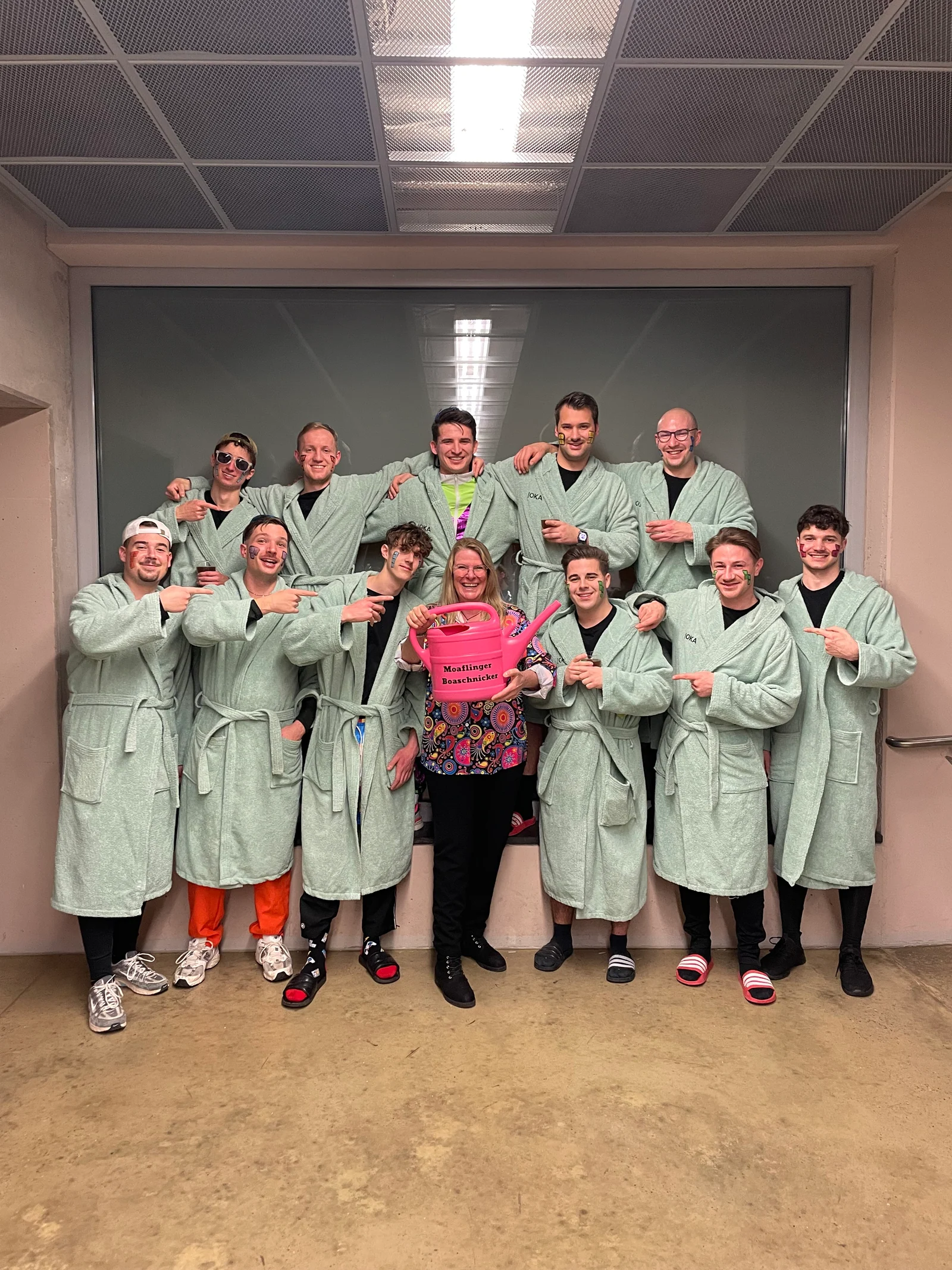 Gruppenfoto in hellgrünen Bademänteln mit pinken Gießkannen.
